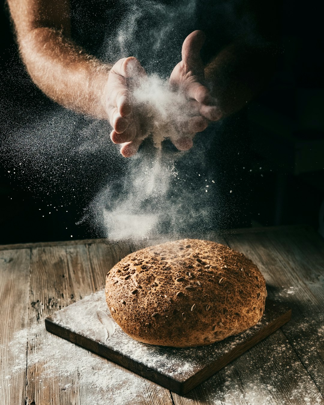 Mains d'un boulanger façonnant un pain dans la farine